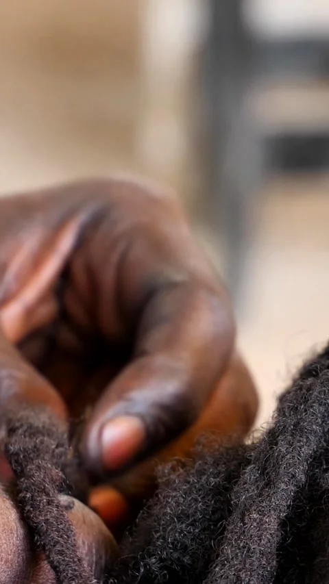 Close shot of black hands tiddying dreadlocks at the base while smoking Video stock 230667945