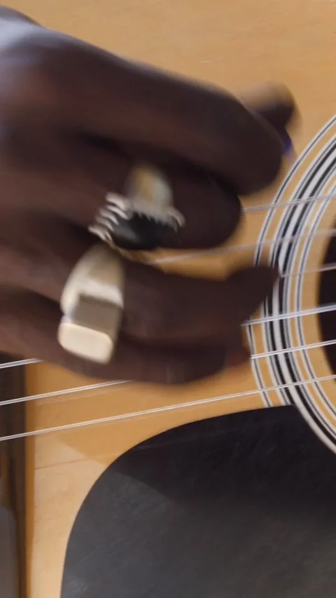 Close shot of black man playing acoustic guitar sitting on chair Video stock 228843224