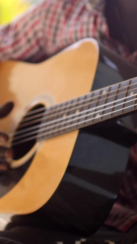 Close shot of black man playing acoustic guitar sitting on chair Stock Footage 230664457