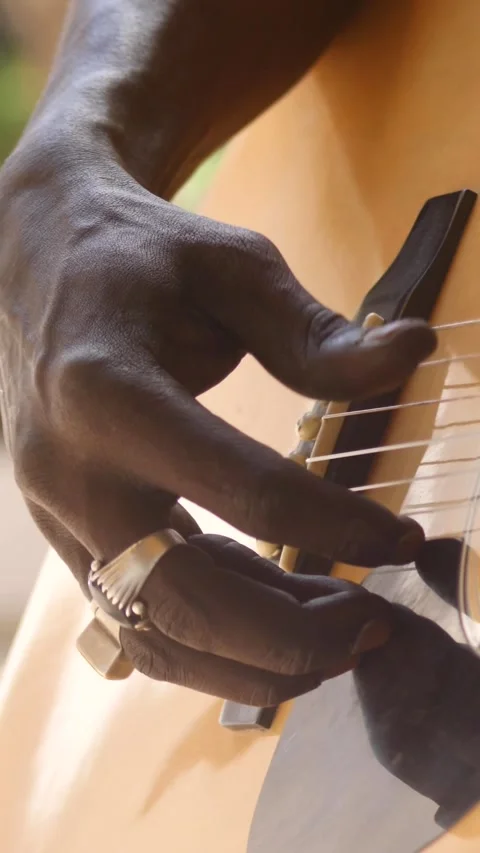 Close shot of black man playing acoustic guitar sitting on chair Video stock 230664518