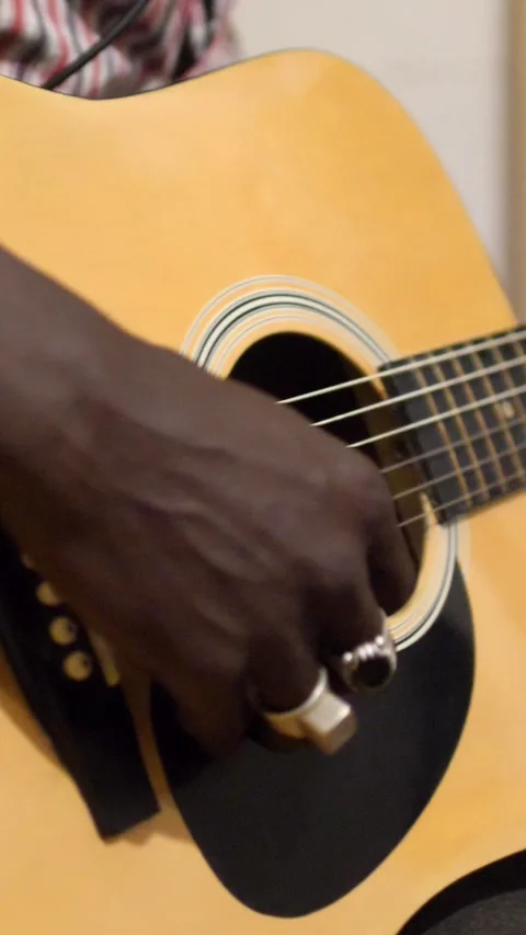 Close shot of black man playing acoustic guitar sitting on chair Stock Footage 230664850