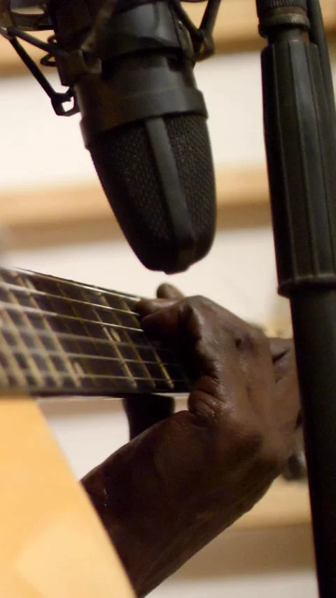 Close shot of black man playing acoustic guitar sitting on chair Stock Footage 230664911