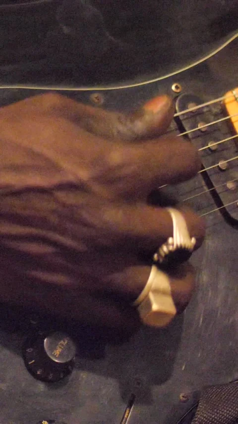 Close shot of black man playing electric guitar sitting on chair Video stock 230665107