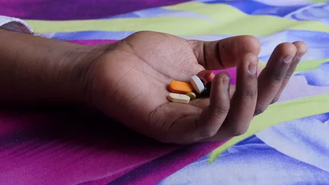 Close shot of a black man's hand lying on the floor, palm filled with medicines Stock Footage 147100279