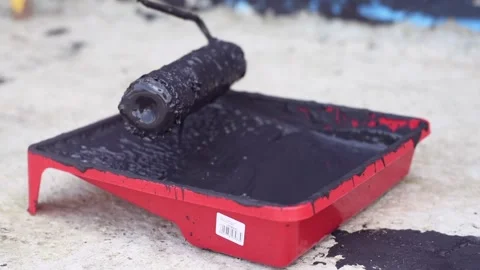 Close up shot of black paint being loaded onto a roller in red paint tray. Stock Footage 339412091