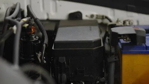A close-up shot of a black plastic engine fuse box cover next to a car Stock Footage 336710341