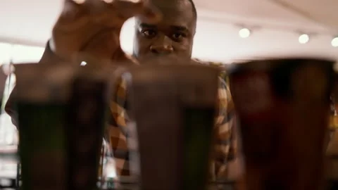 Close-up shot of a Black-skinned man walks up to the counter and picks up a Stock Footage 247050909