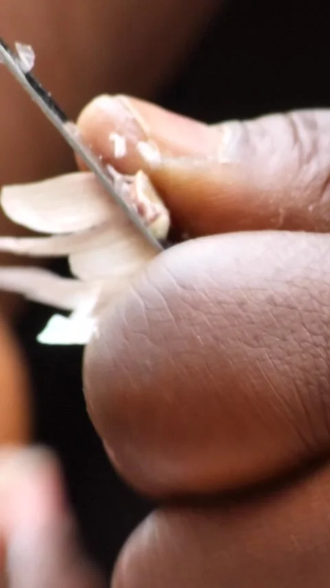 Close shot of black woman hands removing skin of garlic clove with knife 스톡 동영상 230665341
