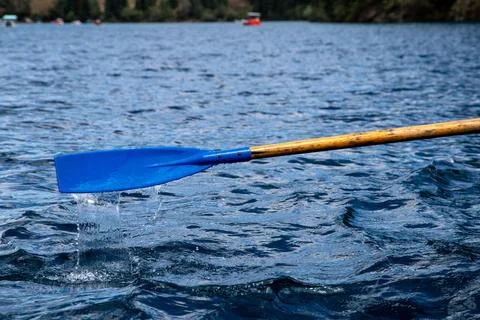 Close Up shot of blue paddle on small boat with calm lake water Stock Photos