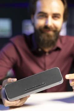 Close up shot of bluetooth portable speaker presented by cheerful online star Stock Photos