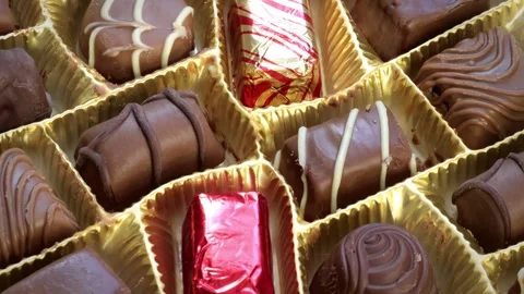 Close-up shot of a box of milk chocolates slowly rotating in a circular motion Stock Footage 247515635