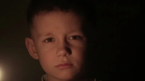 Close-up shot of a boy in a darkness with a lit candle in hands Stock Footage 172390723