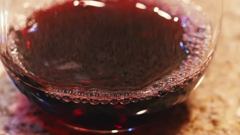 Close up shot of bubbles in red wind in a glass on a granite countertop Video stock 255139261