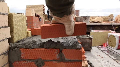 Close shot at the builder hands, the man puts the bricks on concrete, for Stock Footage 115329862