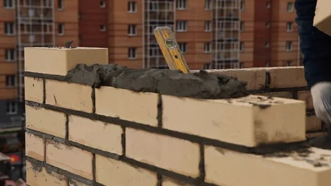 Close shot at the builder hands, the man puts the bricks on concrete, for Stock Footage 115329879
