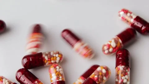 Close up shot of capsules with multi-colored granules fall on a white surface 库存影片 274503142