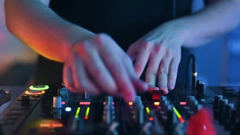 A close-up shot captures the hands of a DJ actively mixing music on a Stock Footage 323606417