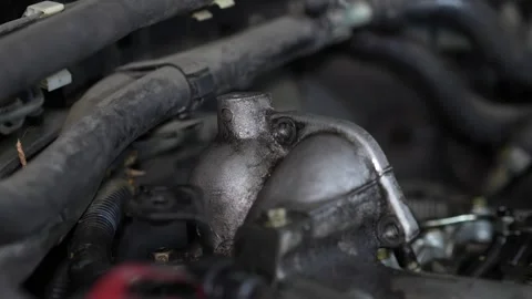 A close-up shot captures a metallic engine thermostat housing or similar alum Stock Footage 345107085