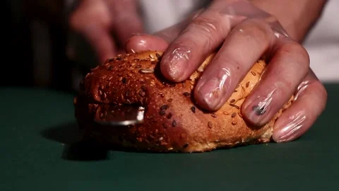 A close shot captures a persons hand pressing the top seeded bun onto a stacked Video stock 309656171