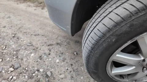 Close-up shot of a car tire resting on a dirt and gravel road. The detailed v Stock Footage 346296957