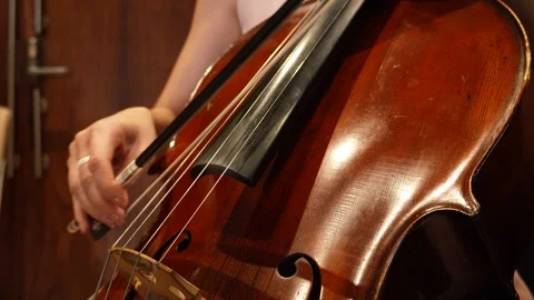 Close-up shot of a cellists hand gracefully moving the bow across cello strings. Stock Footage 313741064