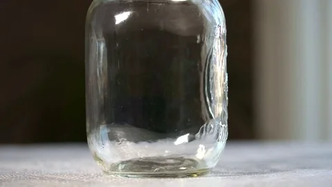 Close up shot of change falling into an empty jar until half way full. Stock Footage 69918624