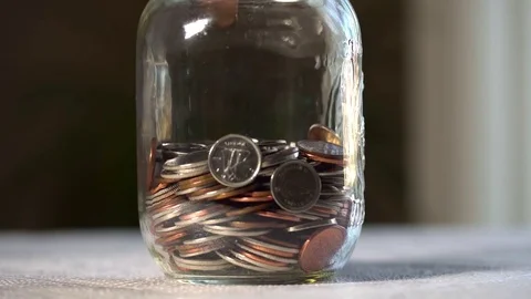 Close up shot of change falling into a half full jar until it is full. Stock Footage 69918708