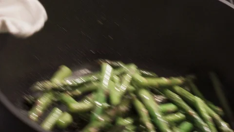 A close shot of chef cooking fresh asparagus in a deep pan Stock Footage 100396107