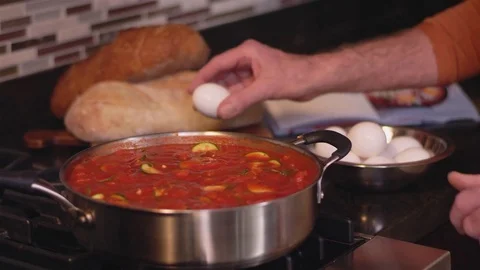 Close up shot of a chef cracking an egg onto a broth cooking in a pot Vidéo 83023338