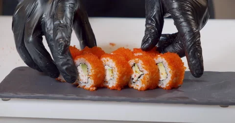 Close-up shot of a chef hands in black gloves serving delicious sushi with Stock Footage 150358251