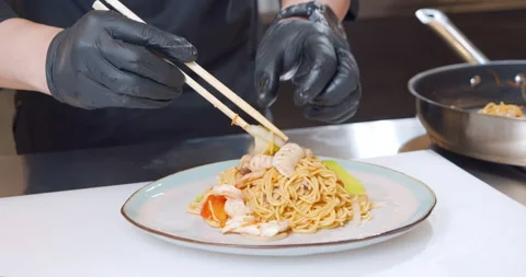 Close-up shot of a chef hands in gloves putting delicious egg noodles with Stock Footage 150670541