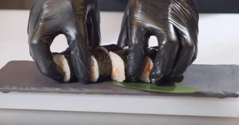 Close-up shot of a chef hands in gloves laying out delicious sushi rolls with Stock Footage 150964361