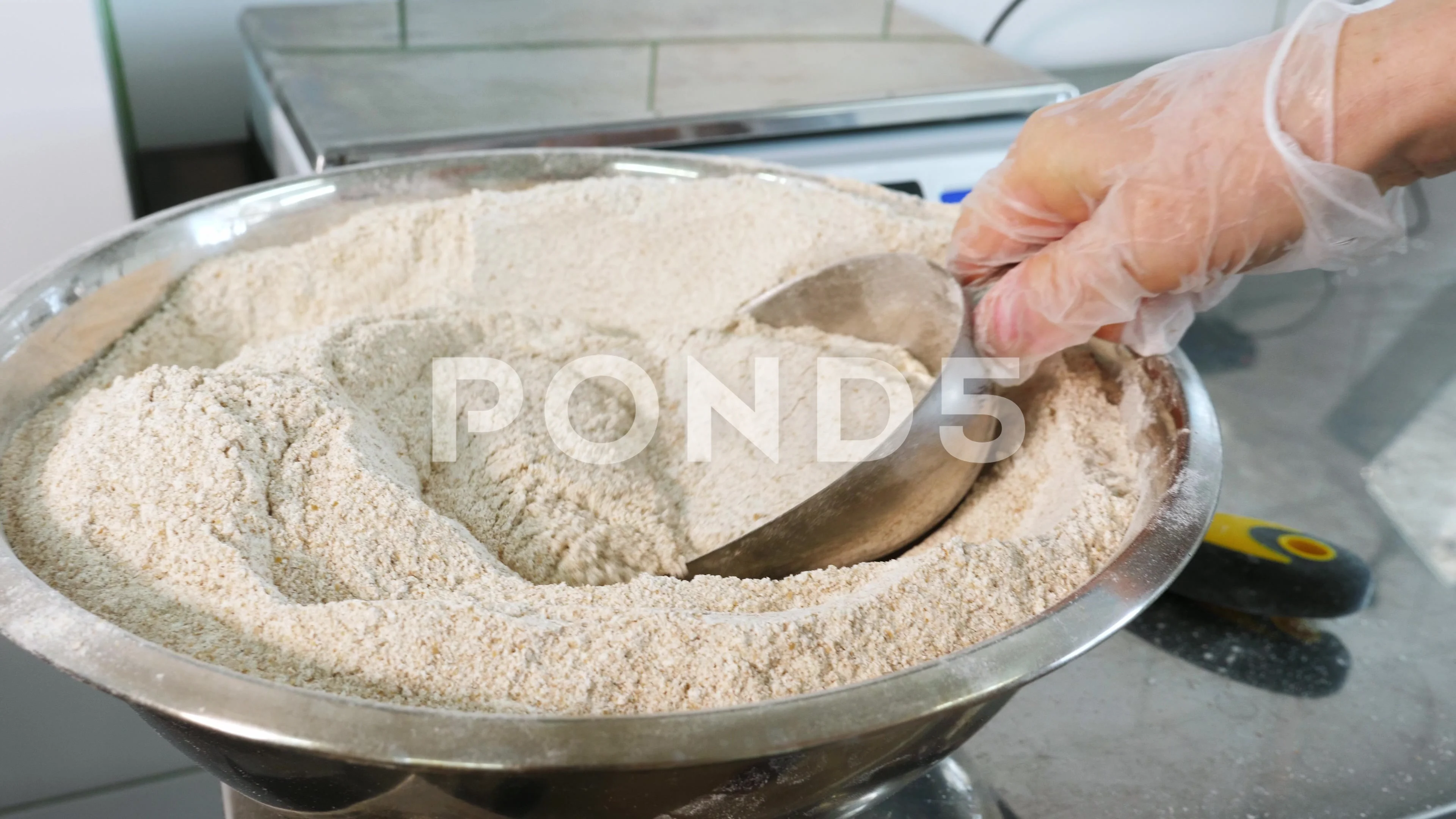 Pastry chef pouring flour with help of wooden spoon to blender