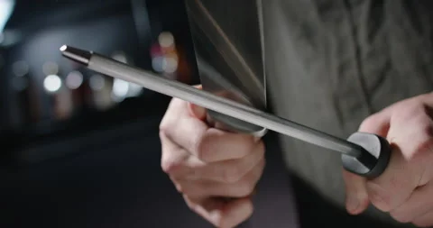 Close up shot of chef sharpening a cool knife before cutting meat or making a Stock Footage 143287698