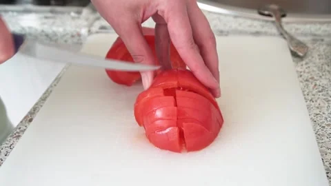 Close up shot of a chef's hands cutting a fresh tomato with a knife on a white Stock Footage 182379748