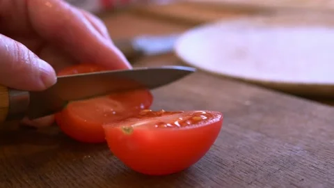 Close up shot of chef's hands cutting fresh tomato with knife on wooden board Vidéo 220143133
