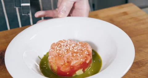 Close-up shot of chef's hands in gloves preparing delicious salmon and tomato Stock Footage 153353624