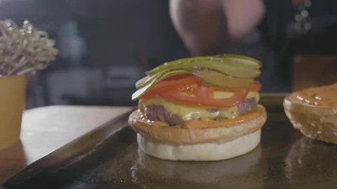 Close-up shot of chef's hands preparing a hamburger with beef rissole and cheese Stock Footage