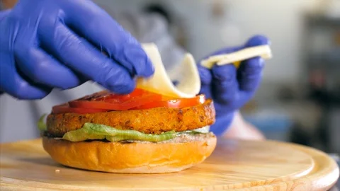 Close-up shot of chef's hands preparing a delicious burger with cheese. Stock Footage 121089289