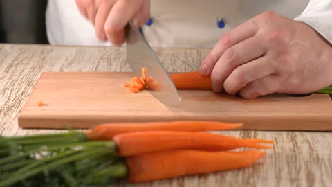 Close up shot of chef's hands using a knife cutting a fresh carrot Stock Footage 157420251