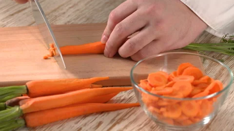 Close up shot of chef's hands using a knife cutting a fresh carrot Stock Footage 157421145