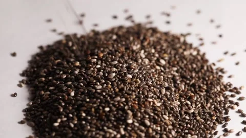 Close-up shot of a chia seed falling and spinning on a white table. 60 fps Stock Footage 152868443