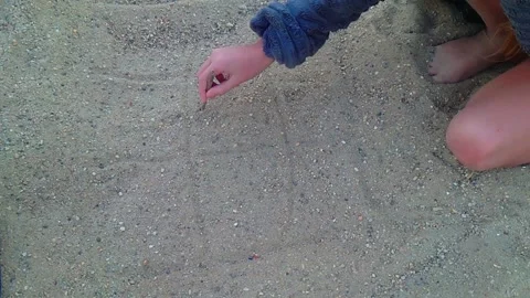 Close Up Shot of Child Hand Drawing Tic Tac Toe Grid in Sand with Stick Flava Stock Footage 345309928