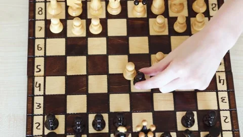 A close-up shot of a child's hand moving a pawn on a chessboard. The board is Stock Footage 278900403