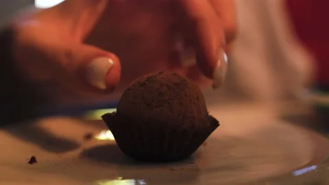 Close-up shot of chocolate candy in paper with cocoa powder, hand takes a candy Stock Footage 139437474