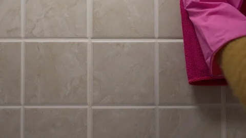 Close up shot of cleaning the tile wall with hand in rubber glove by napkin Stock Footage 98373743