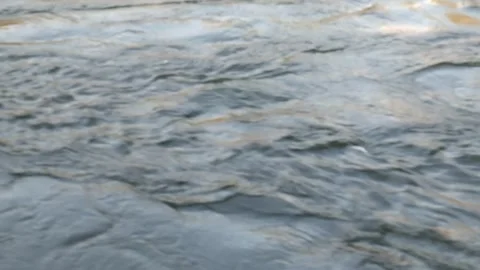 A close-up shot of clear river water flowing steadily over smooth stones. Stock Footage 328444568
