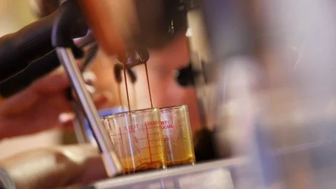 Close up shot, Coffee flows from the coffee maker into the glass. 動画素材 128595805