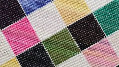 A close-up shot of a colorful checkered pattern hand-embroidered in cross-stitch Stock Footage 344842752