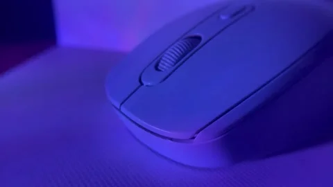 Close-up shot of a computer mouse under colored studio lighting on a clean surfa Stock Footage 326336074